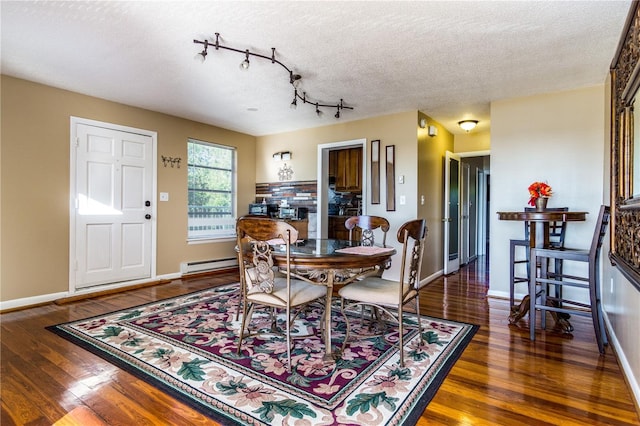 dining space with a baseboard heating unit, a textured ceiling, and dark hardwood / wood-style flooring