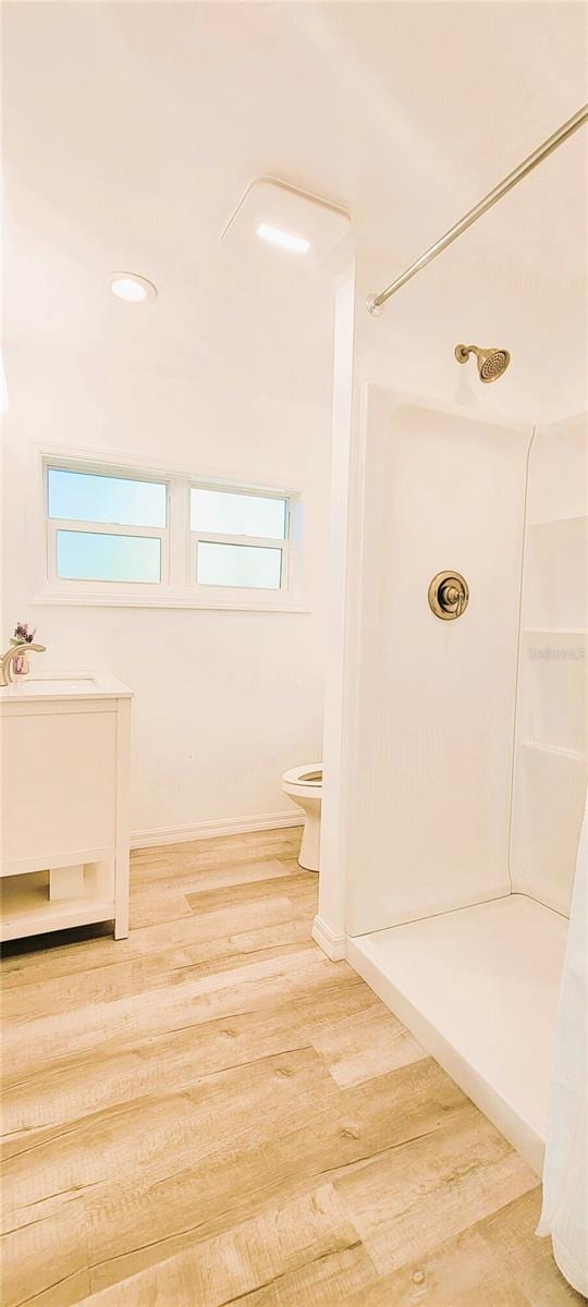 bathroom with walk in shower, toilet, and hardwood / wood-style floors