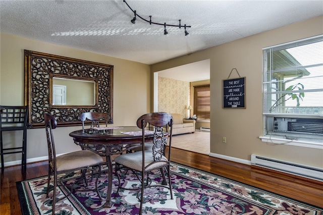 dining room with hardwood / wood-style flooring, a baseboard radiator, rail lighting, and a textured ceiling