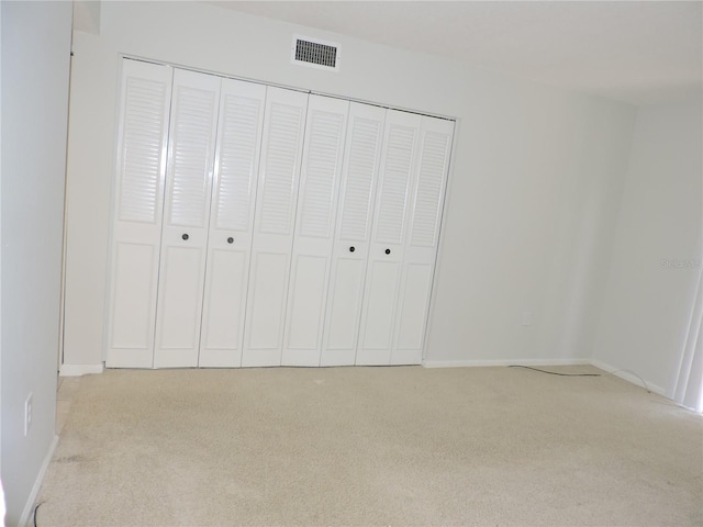 unfurnished bedroom featuring light colored carpet and a closet