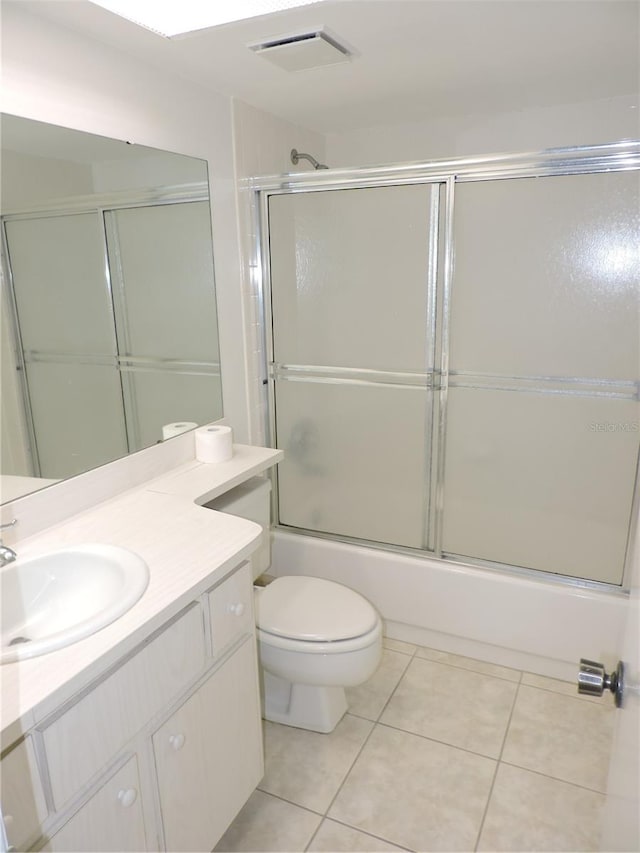 full bathroom featuring tile floors, combined bath / shower with glass door, toilet, and vanity with extensive cabinet space