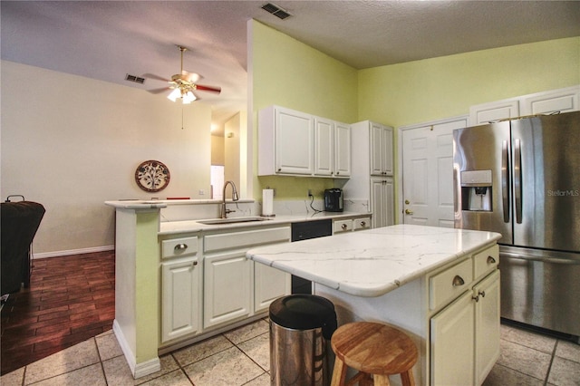 kitchen featuring a kitchen breakfast bar, sink, dishwasher, stainless steel fridge with ice dispenser, and a kitchen island