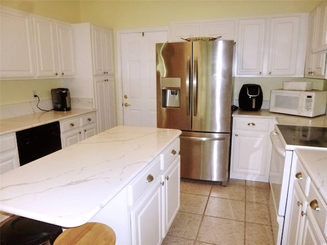 kitchen featuring a kitchen breakfast bar, white appliances, white cabinets, a kitchen island, and light tile patterned flooring