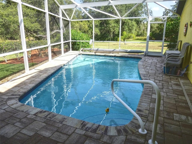 view of pool with a lawn, glass enclosure, and a patio