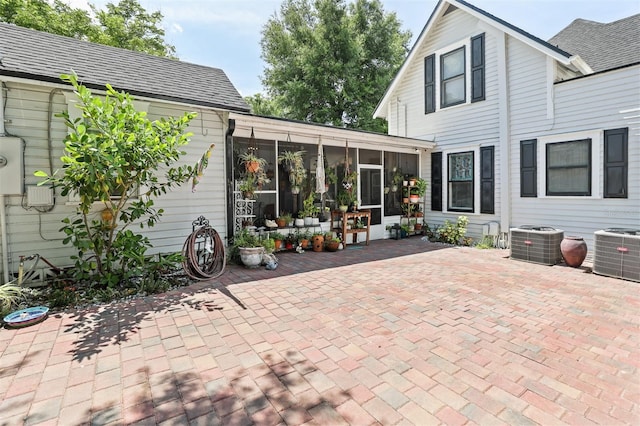 view of patio with central air condition unit and a sunroom