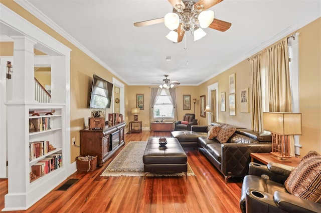 living room featuring hardwood / wood-style flooring, decorative columns, ornamental molding, and ceiling fan