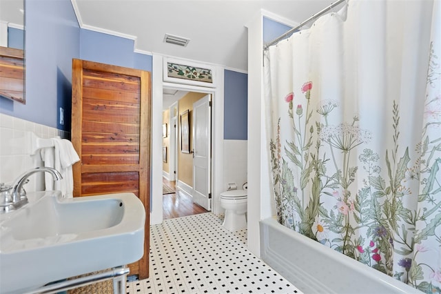 full bathroom featuring ornamental molding, shower / tub combo with curtain, sink, tile walls, and toilet