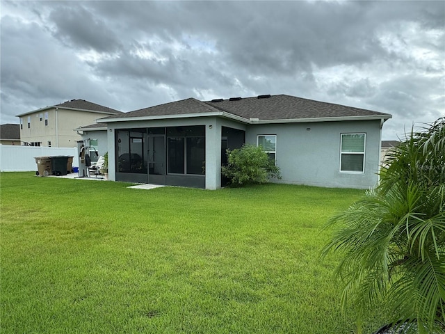 rear view of property featuring a sunroom and a lawn