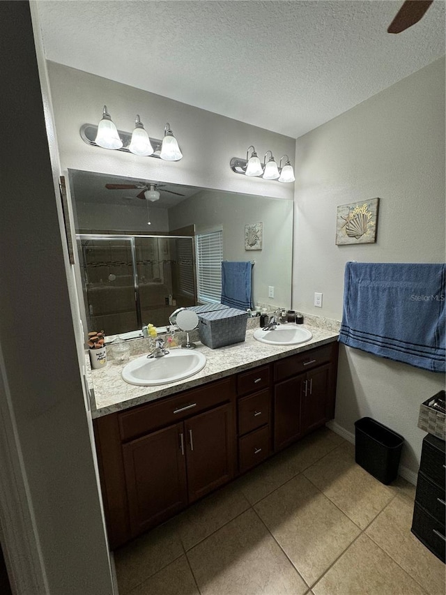 bathroom with a textured ceiling, vanity, ceiling fan, tile patterned flooring, and a shower with shower door