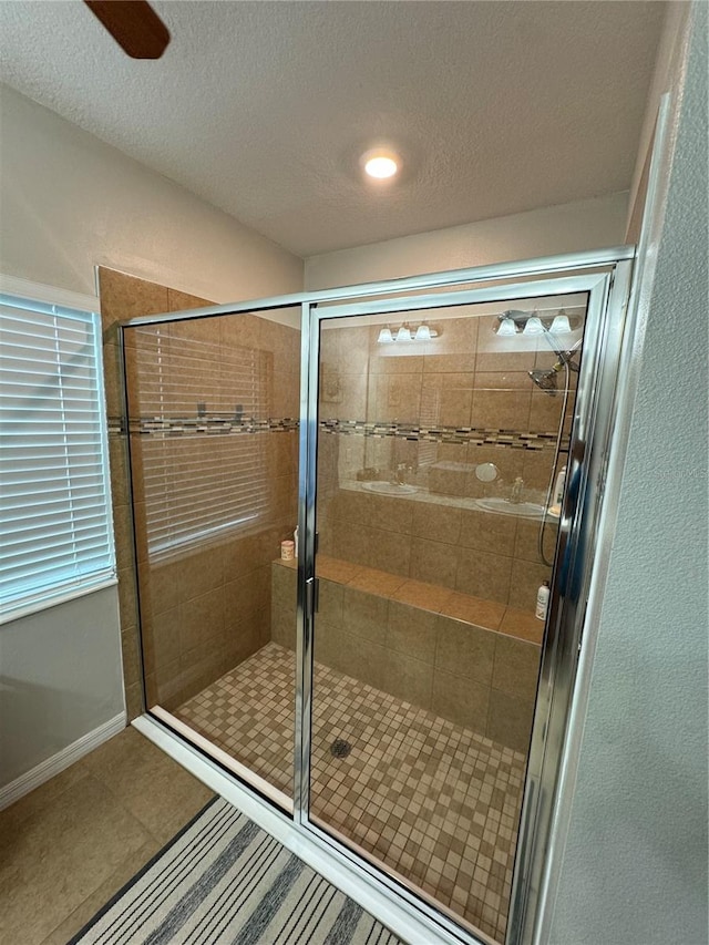 bathroom featuring tile patterned flooring, a shower with shower door, and a textured ceiling