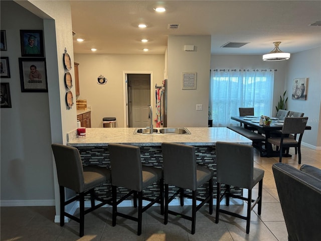 kitchen with kitchen peninsula, sink, a breakfast bar area, and light tile patterned flooring