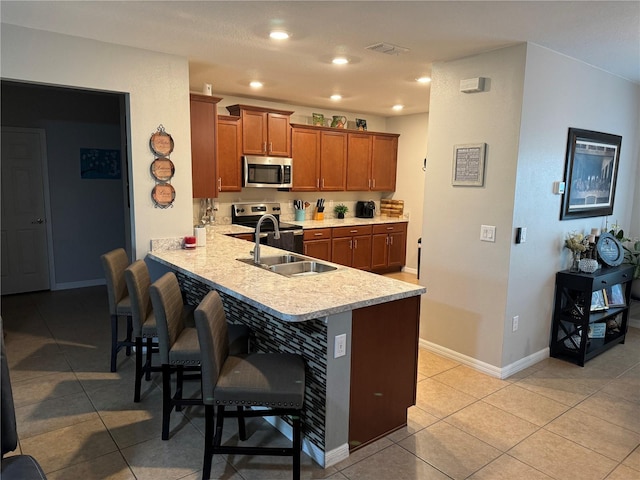 kitchen featuring a breakfast bar area, sink, light tile patterned floors, and stainless steel appliances