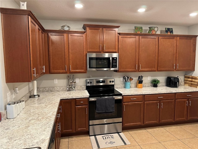 kitchen with light stone countertops, light tile patterned flooring, and stainless steel appliances