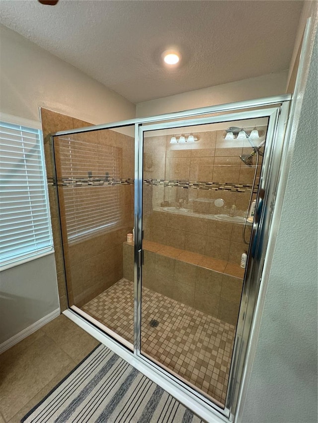 bathroom featuring a textured ceiling, tile patterned floors, and a shower with shower door