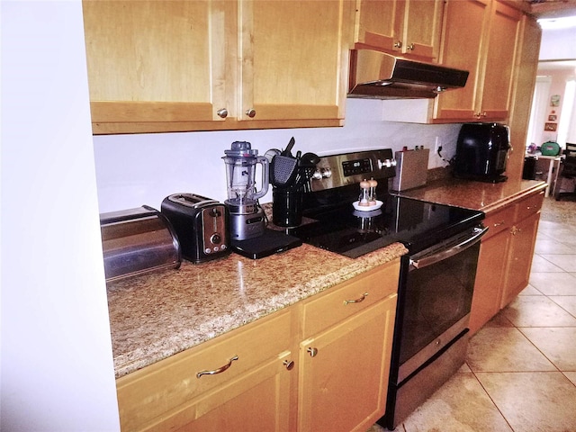 kitchen featuring light tile patterned flooring, light stone counters, and electric range