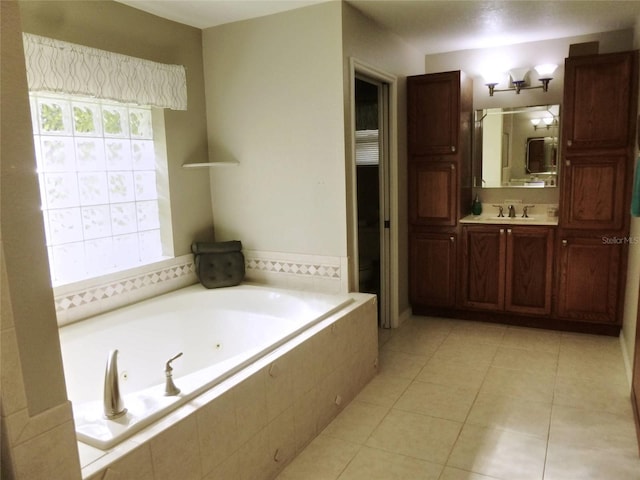 bathroom with tile patterned floors, vanity, and a relaxing tiled tub