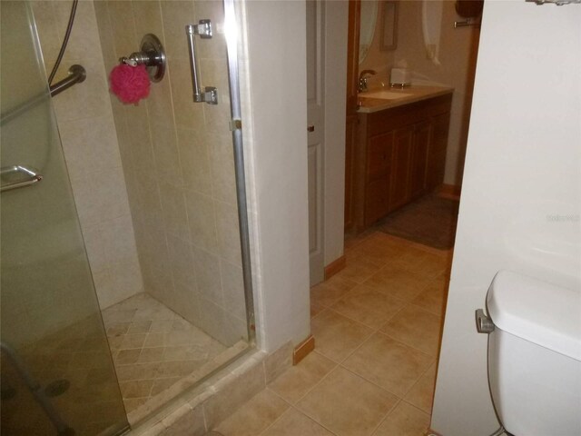 bathroom with walk in shower, vanity, tile patterned flooring, and toilet