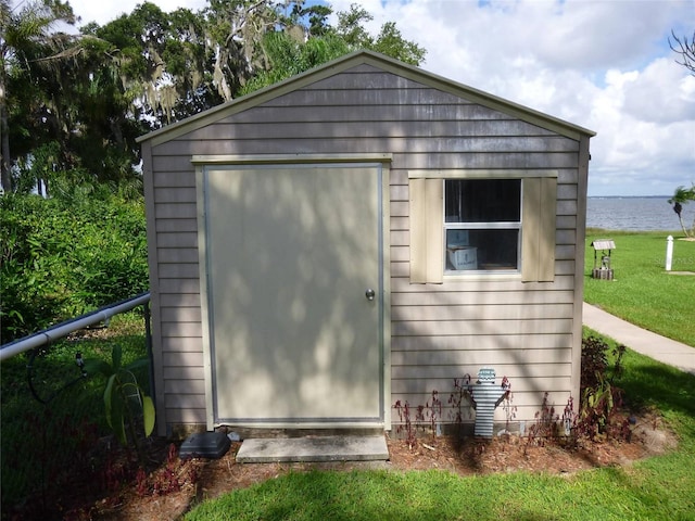 view of outbuilding featuring a lawn and a water view