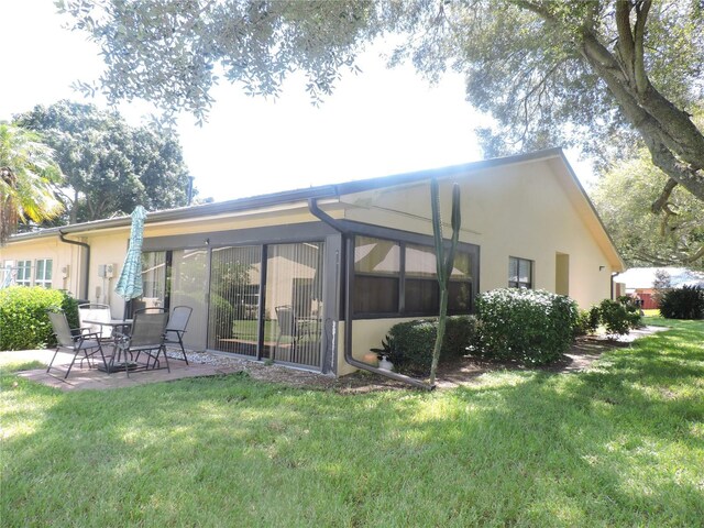 rear view of property with a patio and a lawn