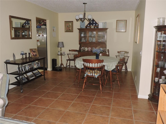 dining area featuring a textured ceiling, an inviting chandelier, and dark tile patterned floors