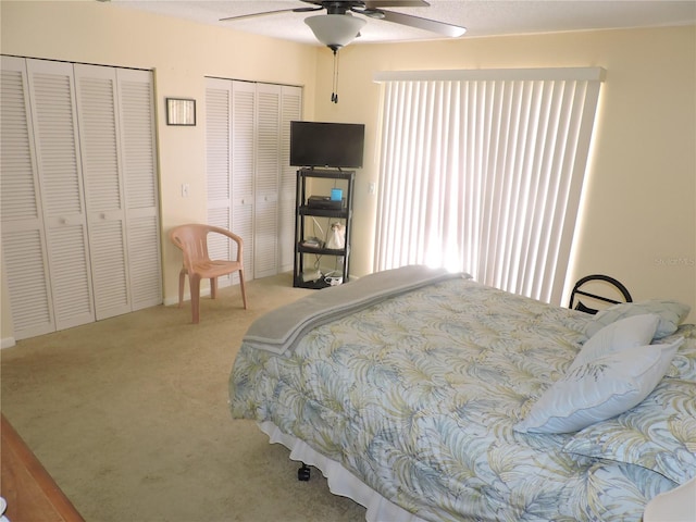 carpeted bedroom featuring two closets and ceiling fan