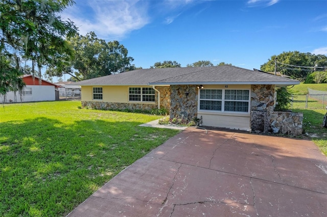 ranch-style home featuring stone siding, fence, and a front lawn