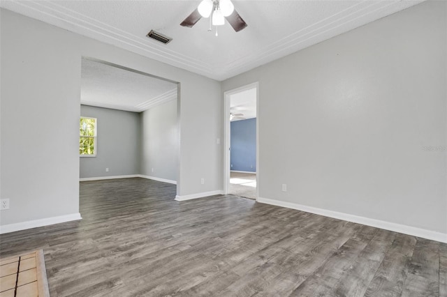 empty room featuring a ceiling fan, visible vents, baseboards, and wood finished floors