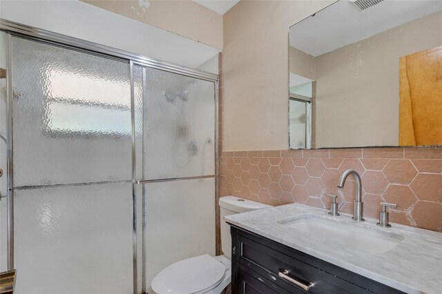 full bathroom with toilet, an enclosed shower, tile walls, and vanity