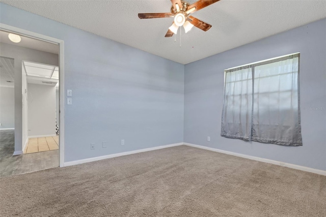 carpeted empty room with ceiling fan, a textured ceiling, and baseboards