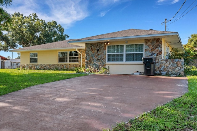 ranch-style home with driveway, stone siding, and a front yard