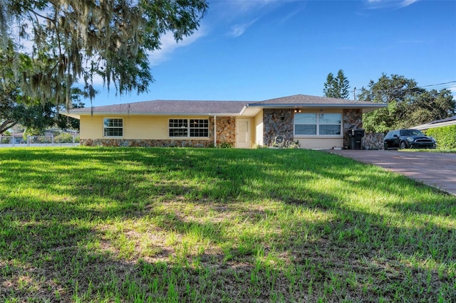 single story home featuring stone siding, fence, and a front lawn