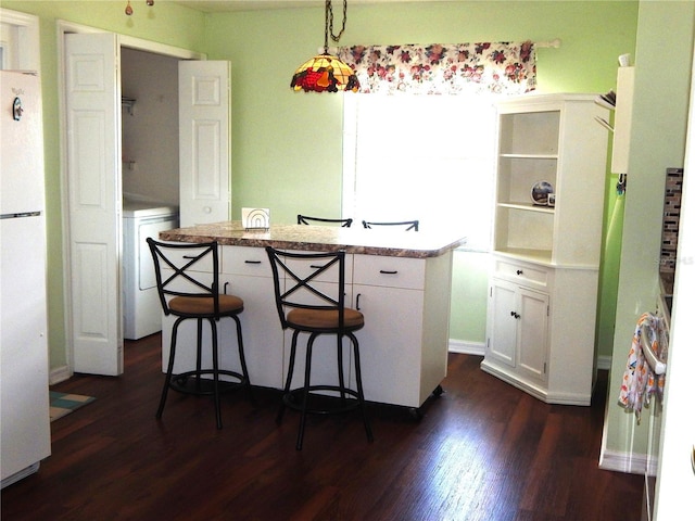 kitchen featuring pendant lighting, white cabinets, a kitchen bar, washer / clothes dryer, and white fridge