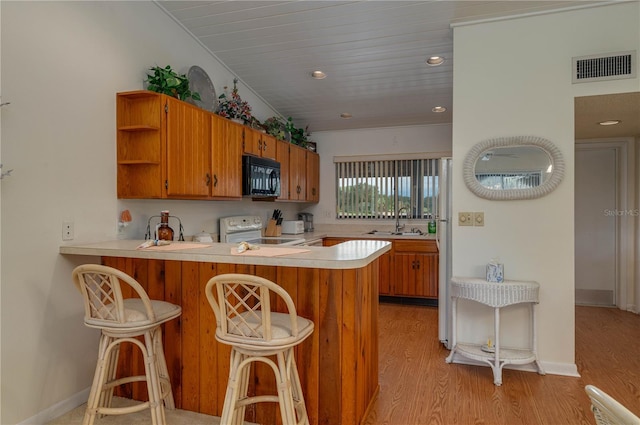 kitchen featuring black microwave, range with electric stovetop, a sink, visible vents, and light countertops