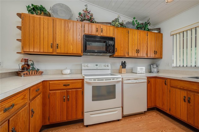 kitchen featuring brown cabinets, light wood finished floors, light countertops, vaulted ceiling, and white appliances