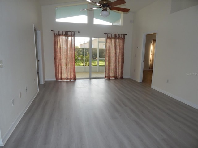 empty room featuring ceiling fan, high vaulted ceiling, and wood finished floors