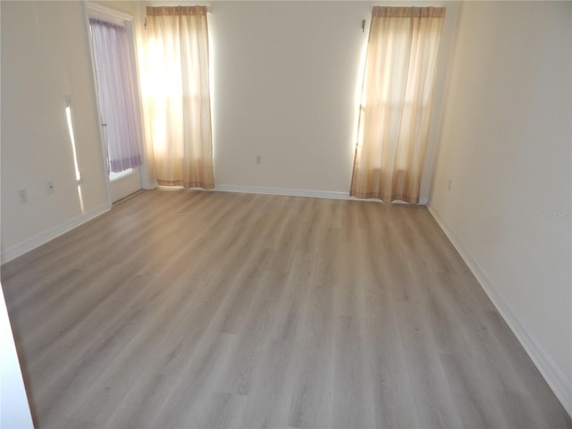 unfurnished room with light wood-type flooring and baseboards