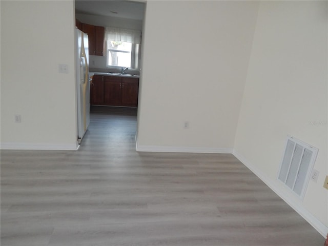 spare room featuring baseboards, visible vents, and light wood finished floors