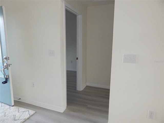 hall with light wood-type flooring and baseboards