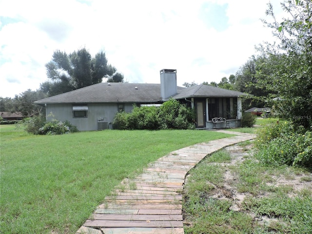 rear view of property featuring a lawn and central air condition unit