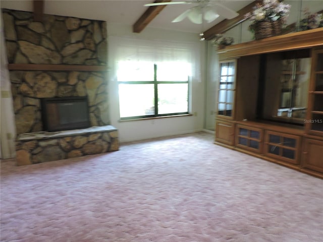 unfurnished living room with ceiling fan, a stone fireplace, light colored carpet, and vaulted ceiling with beams