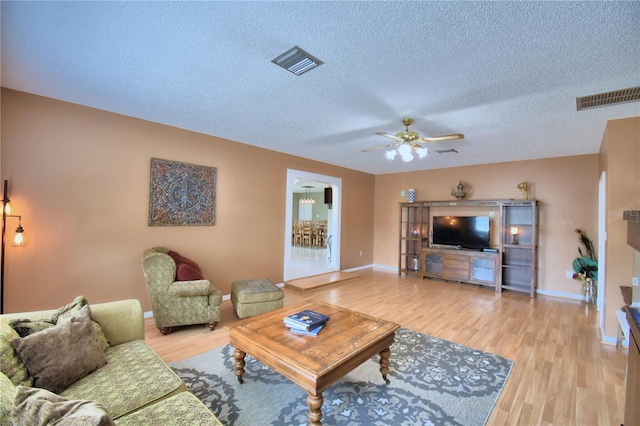 living room with a textured ceiling, wood-type flooring, and ceiling fan