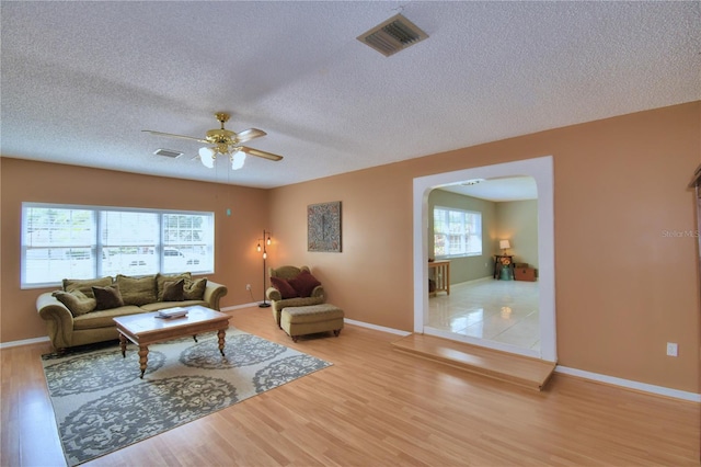 living room featuring a textured ceiling, wood-type flooring, and ceiling fan