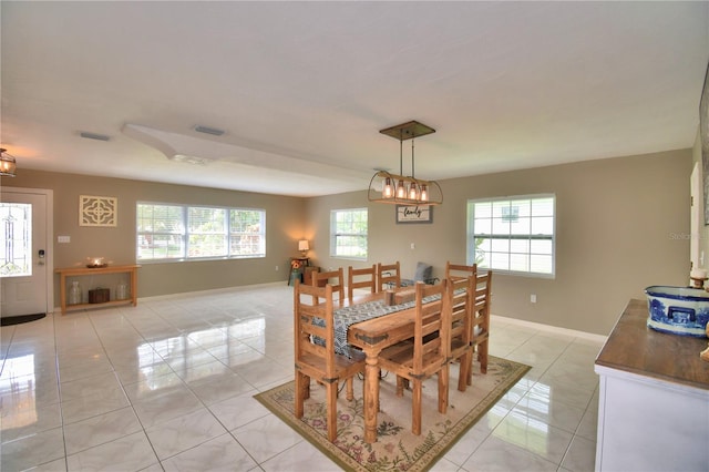 dining room featuring a healthy amount of sunlight, light tile patterned floors, and a chandelier