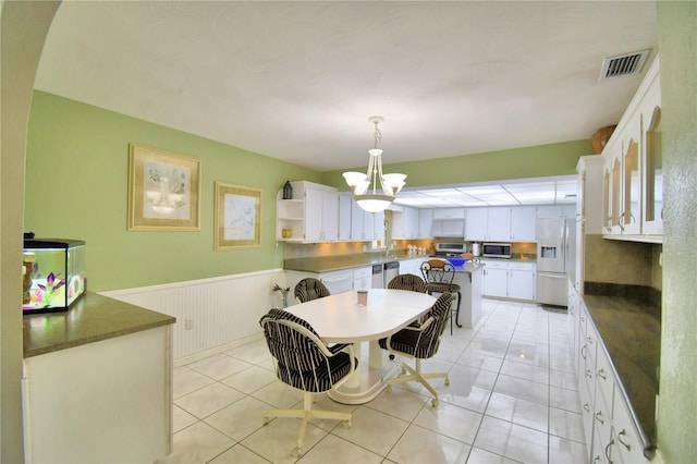 dining area featuring sink, light tile patterned floors, and a notable chandelier