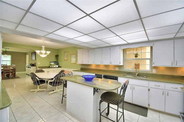 kitchen with pendant lighting, plenty of natural light, sink, a breakfast bar area, and white cabinetry