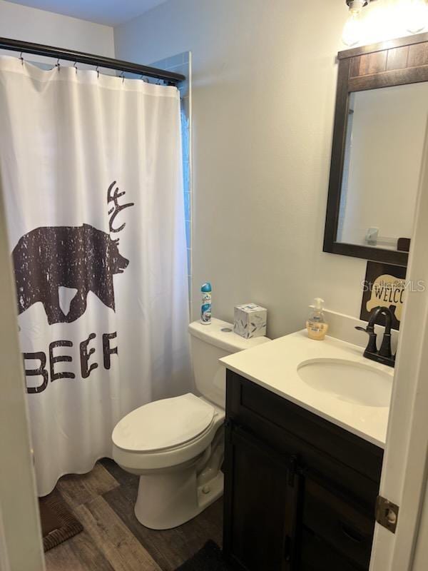 bathroom with a shower with curtain, vanity, toilet, and wood-type flooring