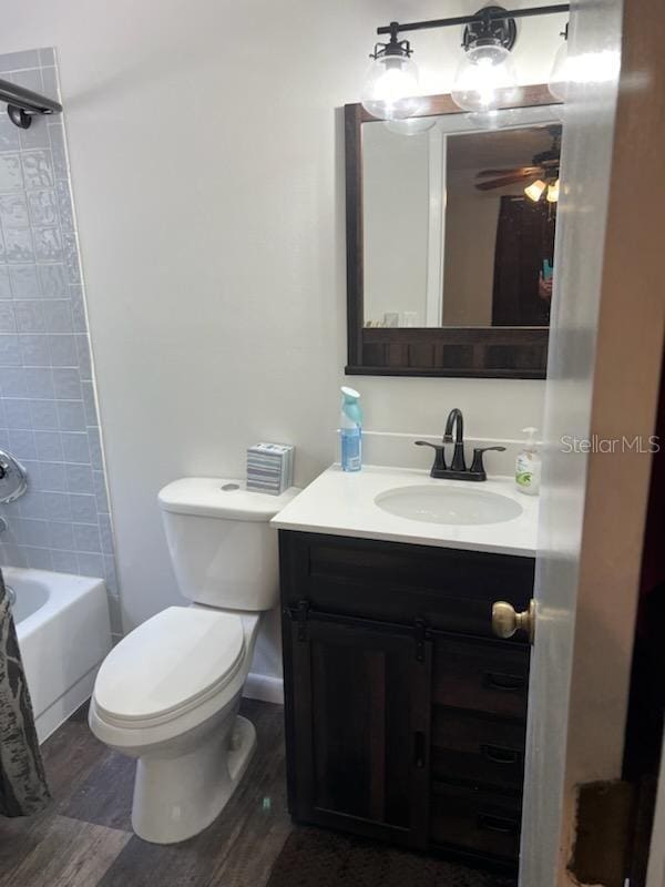 full bathroom featuring hardwood / wood-style floors, vanity, ceiling fan, toilet, and shower / tub combo with curtain