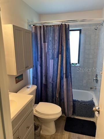 full bathroom with wood-type flooring, vanity, toilet, and shower / bathtub combination with curtain