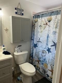 bathroom featuring a shower with shower curtain, vanity, and toilet