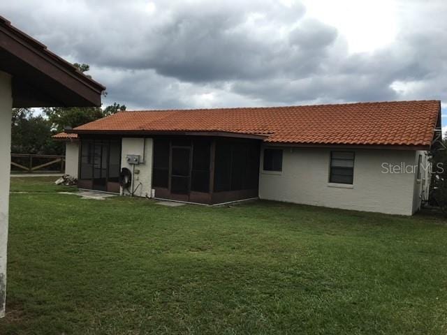 rear view of property featuring a lawn and a sunroom